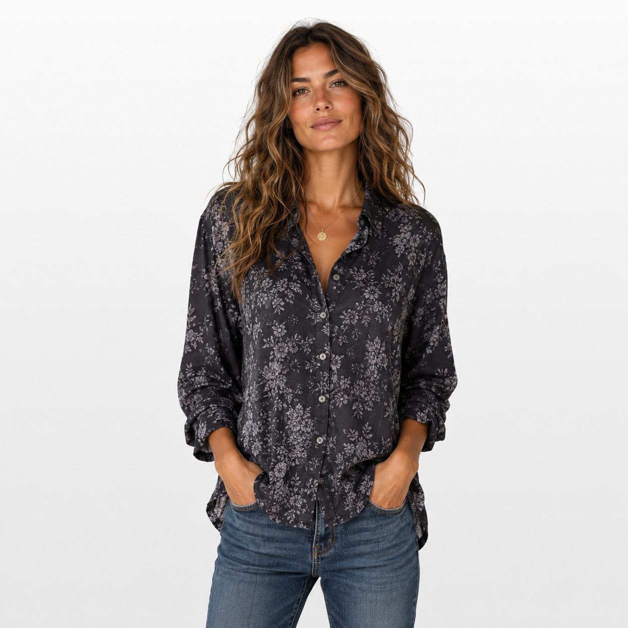 Woman wearing a dark floral blouse and jeans on a white background