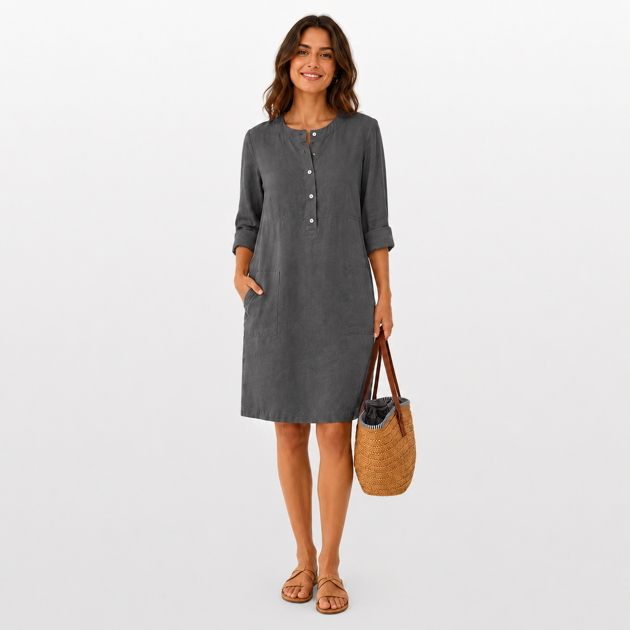 Woman wearing a gray dress holding a woven bag on a white background