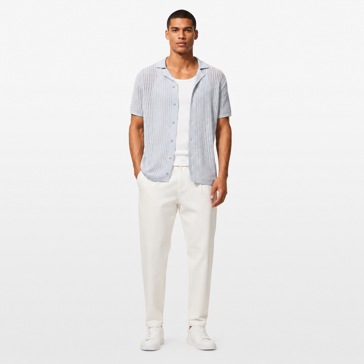 Man wearing a light blue checkered shirt, white pants, and white sneakers on a white background
