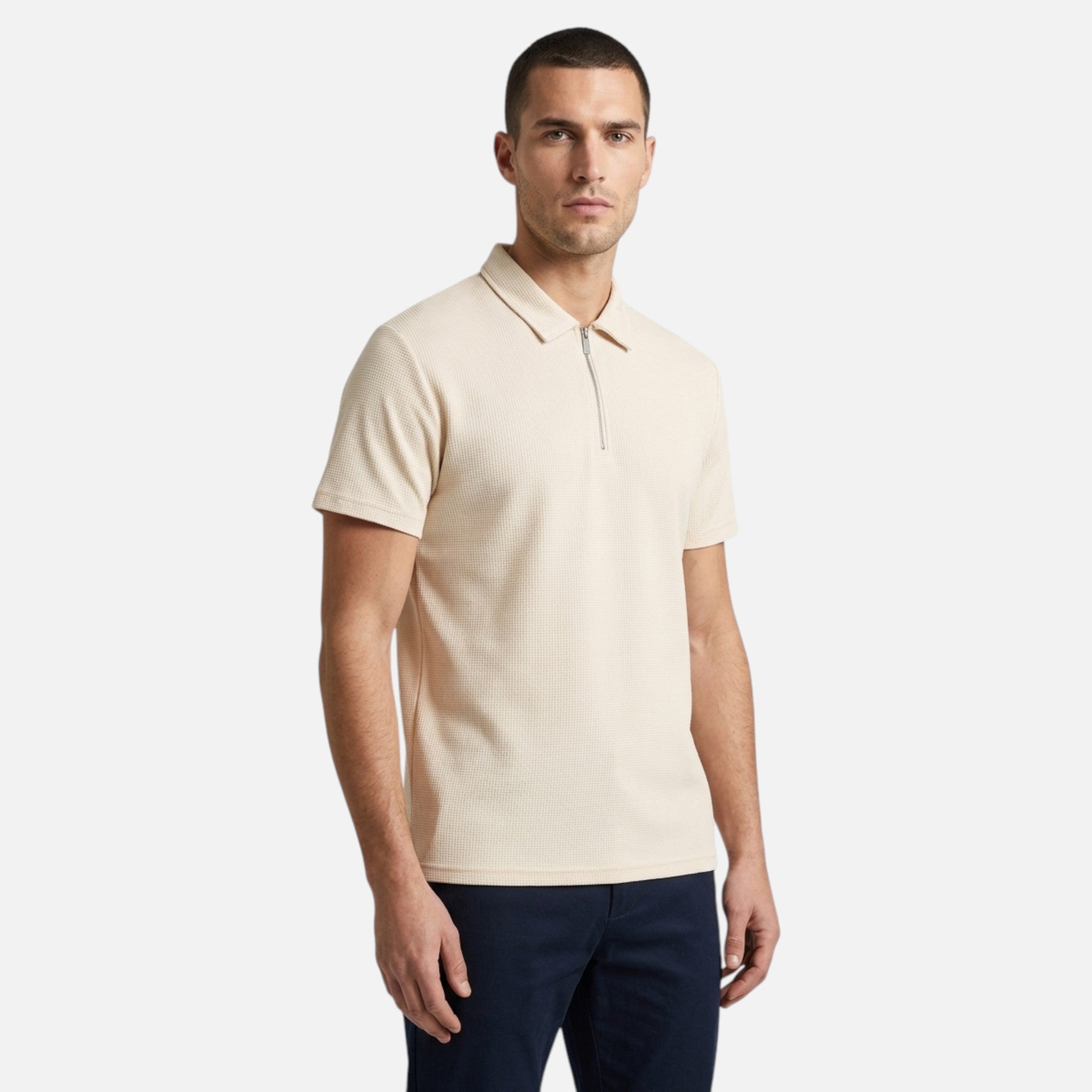 Man wearing a beige polo shirt and dark pants on a white background