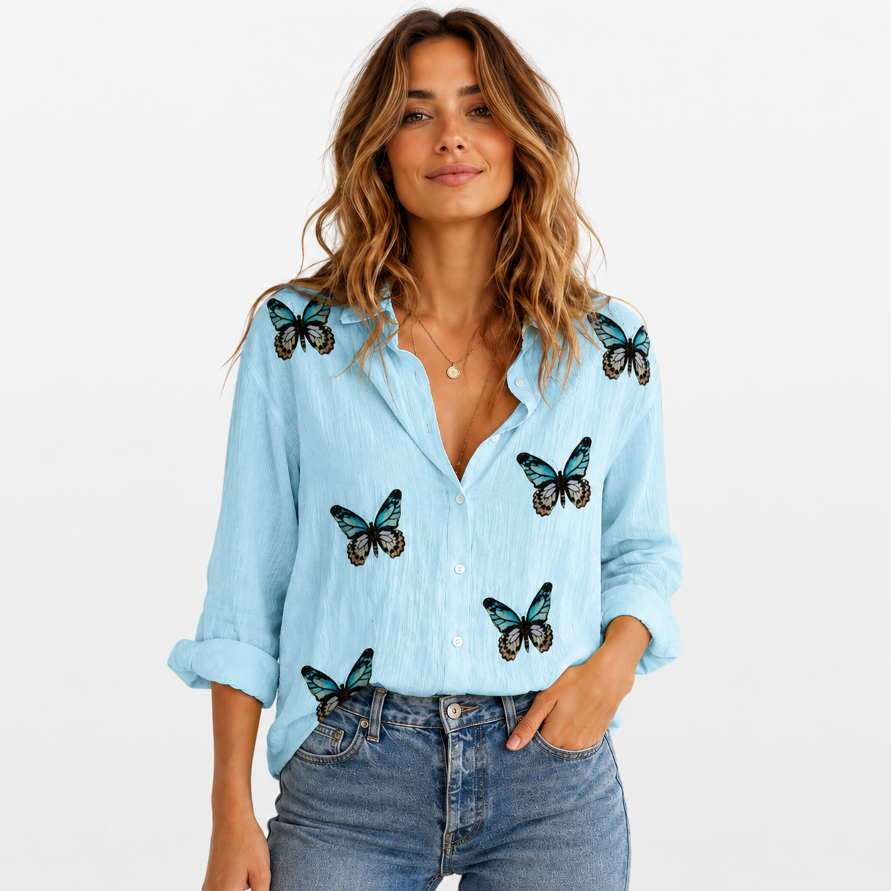 Woman wearing a light blue shirt with butterfly designs on a plain background