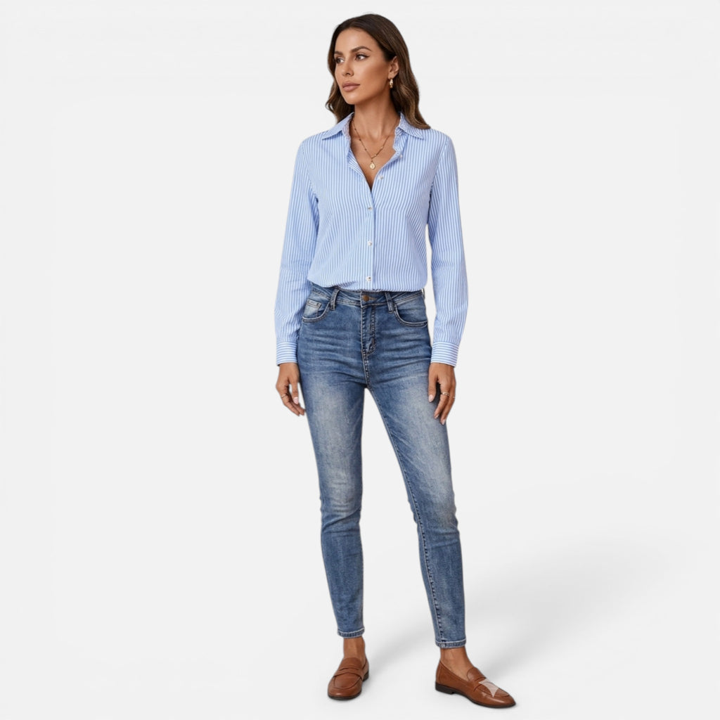 Woman wearing a light blue striped shirt and jeans on a white background