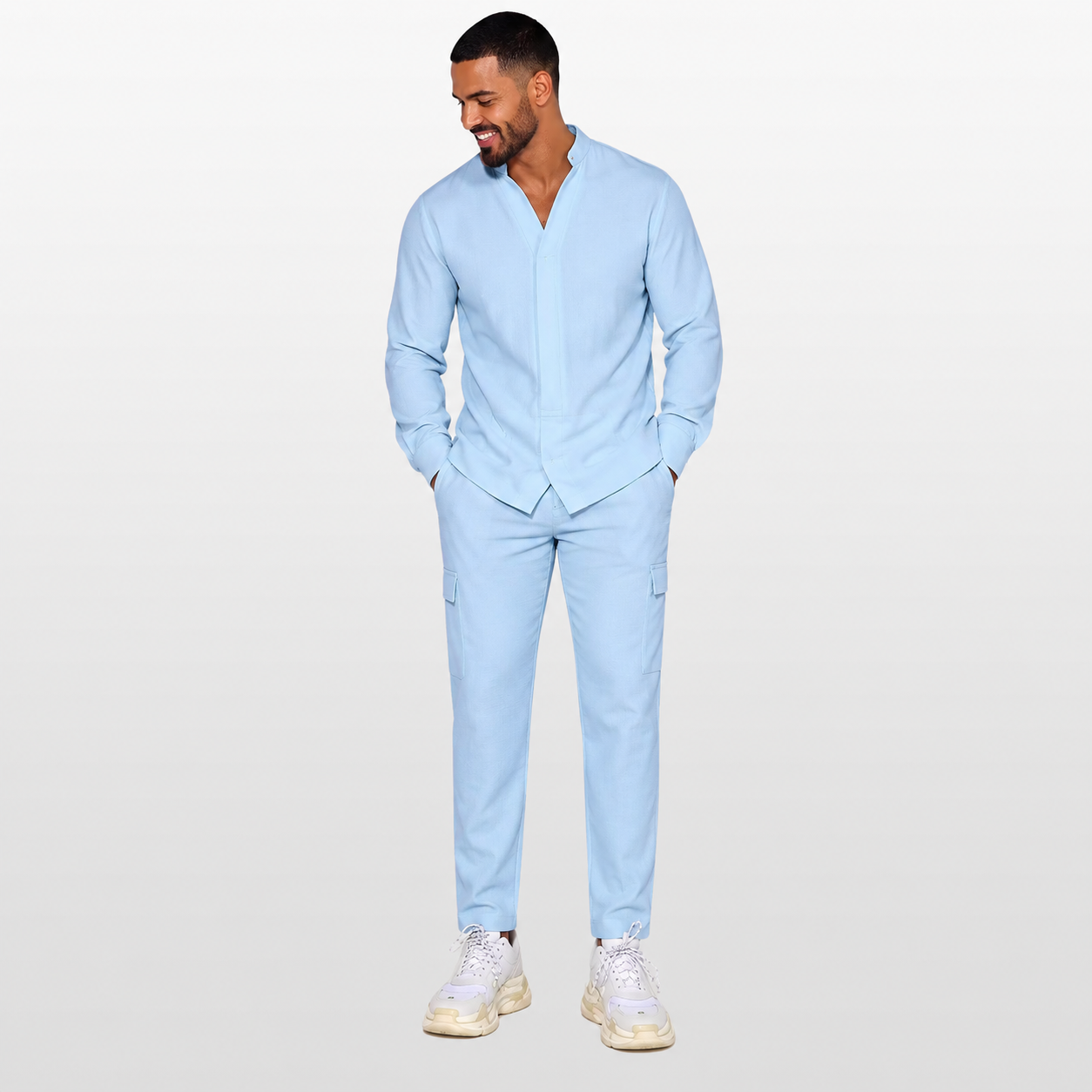 Man wearing a light blue suit with white sneakers on a plain background
