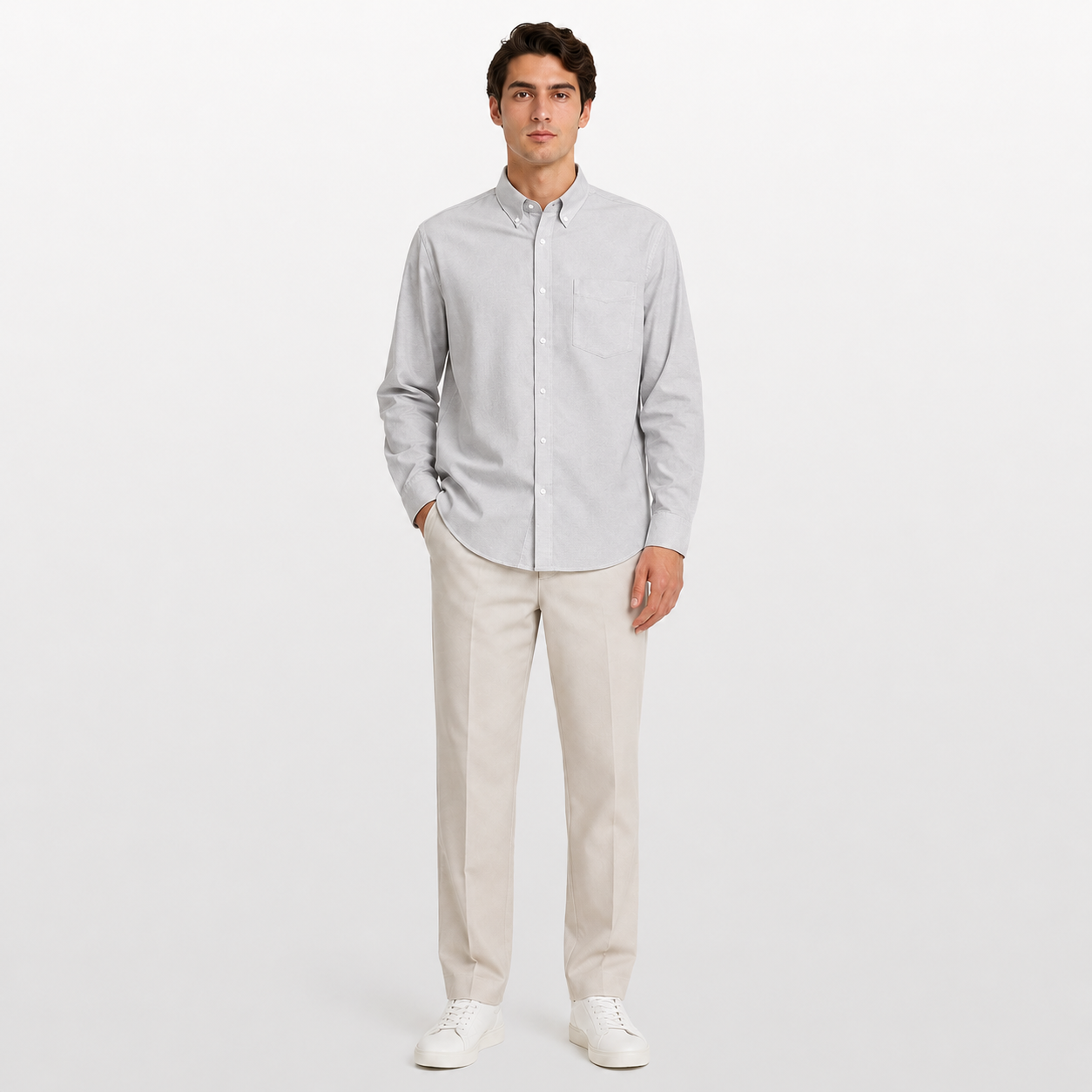 Man wearing a light gray button-up shirt and beige pants on a white background