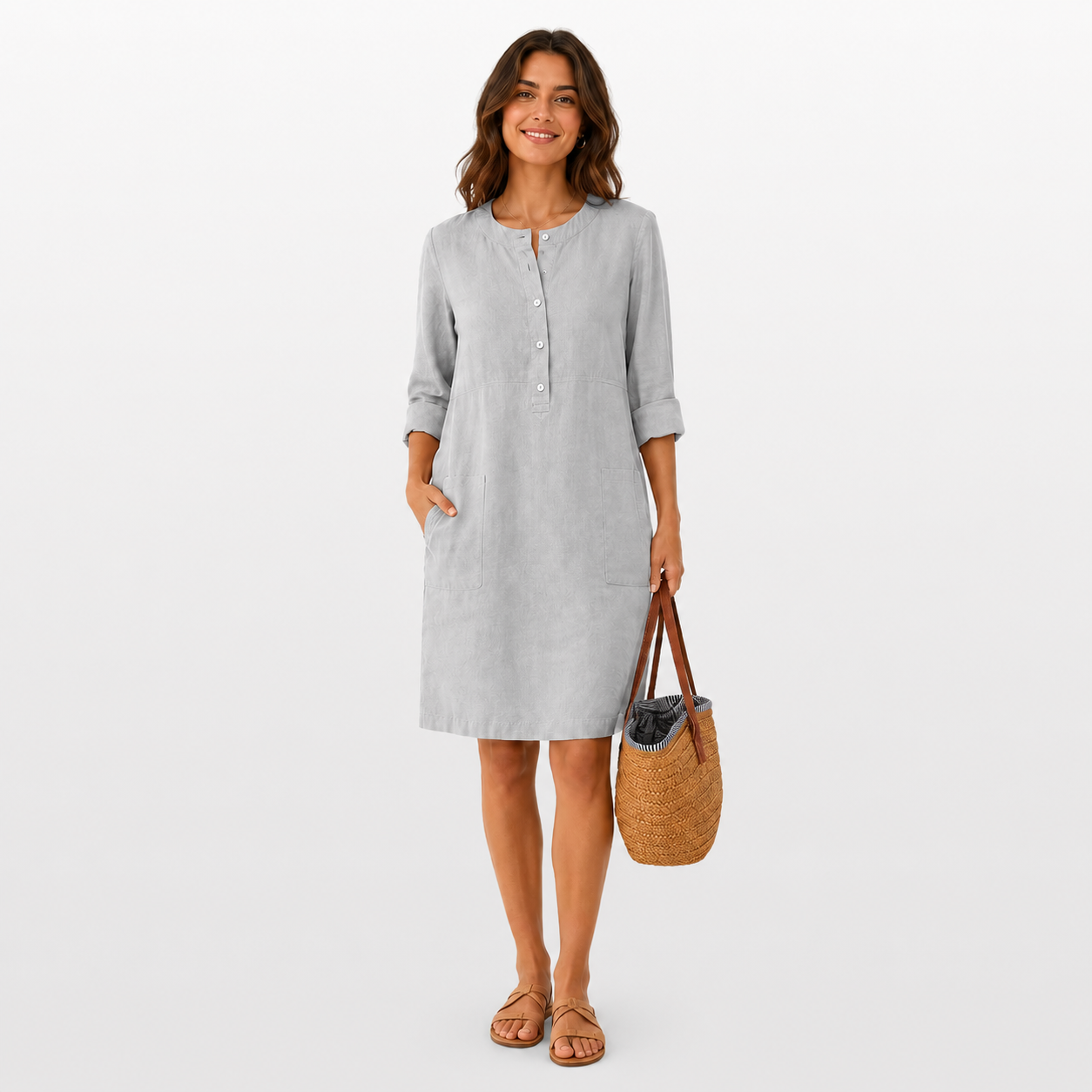Woman wearing a light gray dress holding a woven bag on a white background