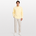 Man wearing a light yellow shirt and beige pants on a white background