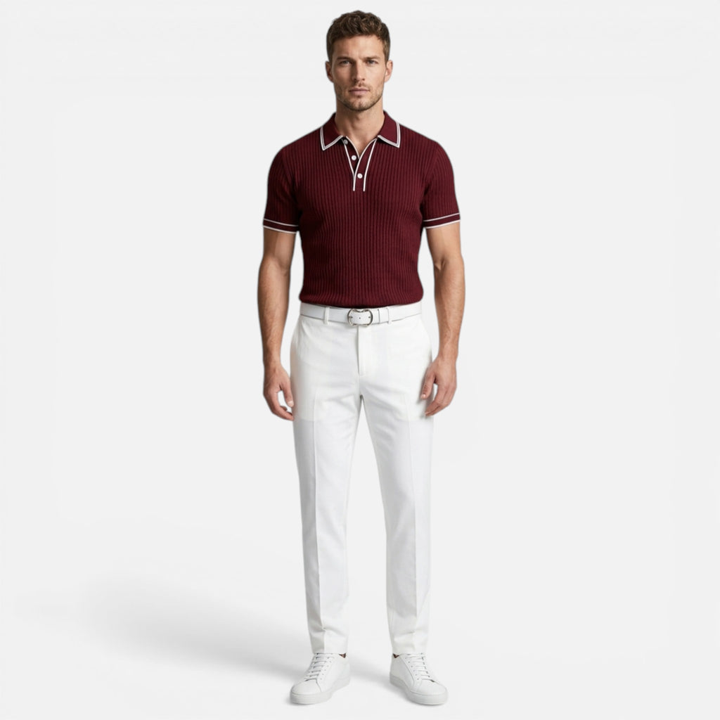 Man wearing a maroon polo shirt and white pants on a white background
