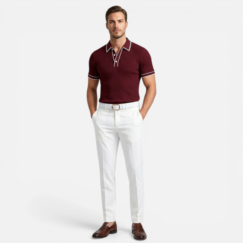 Man wearing a maroon polo shirt and white pants on a light gray background