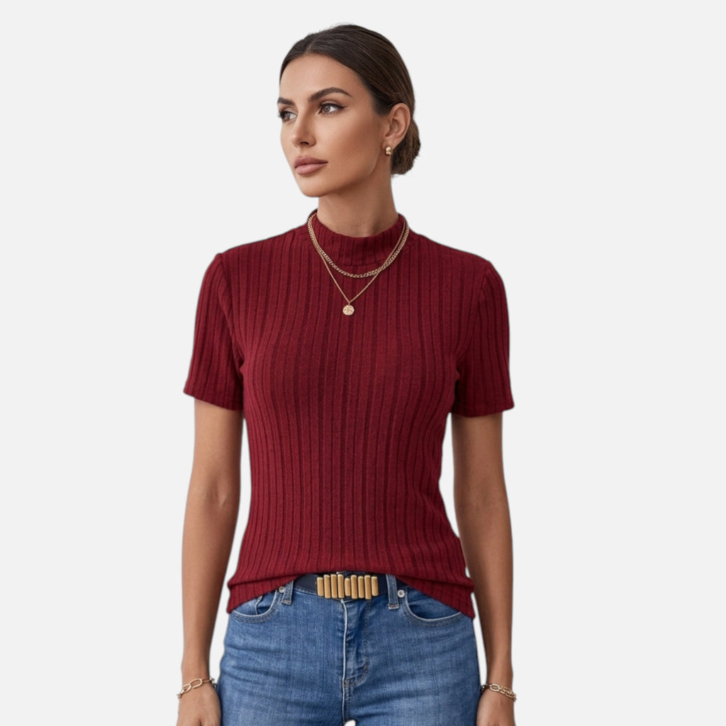 Woman wearing a maroon ribbed sweater and blue jeans on a white background
