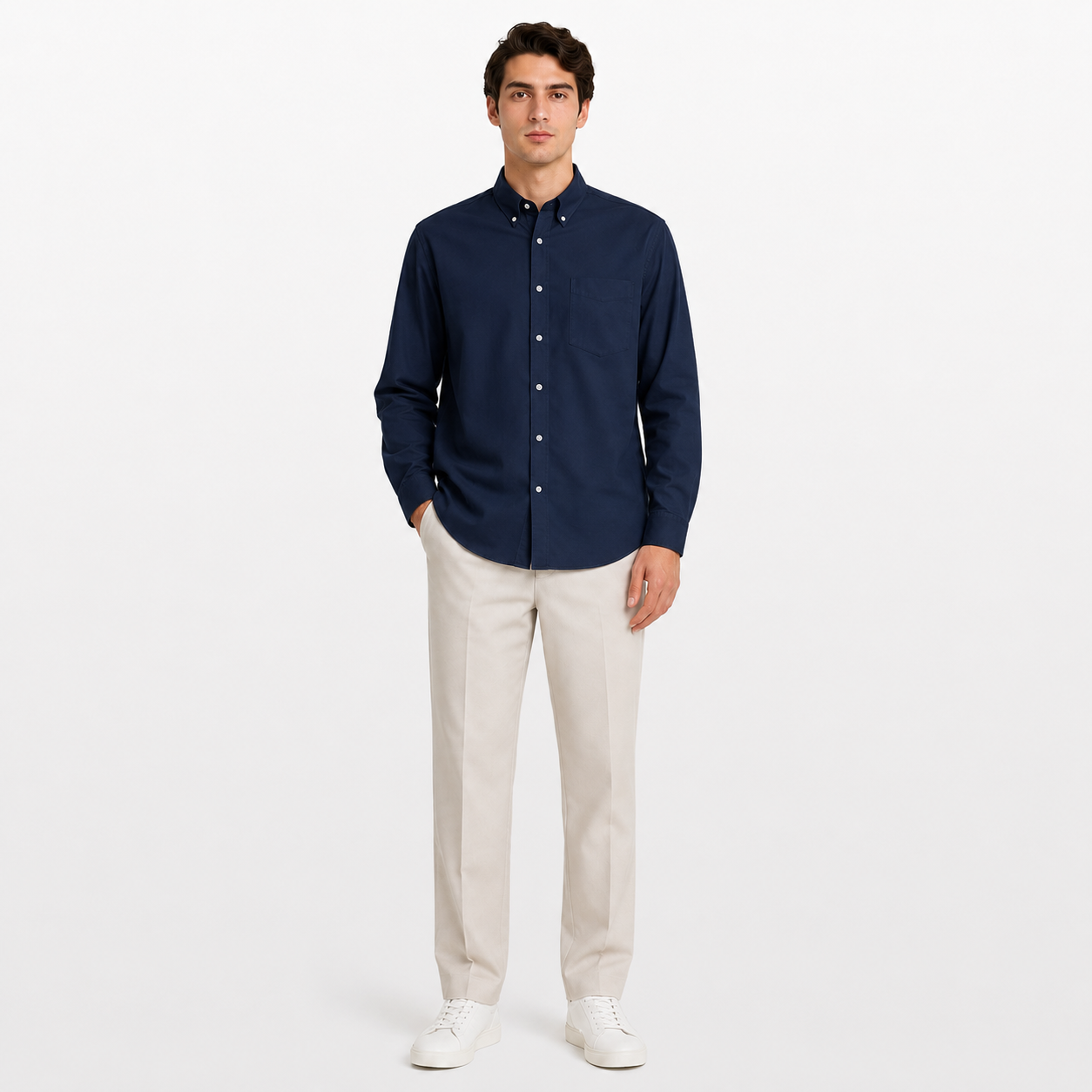 Man wearing a navy button-up shirt and beige pants on a white background