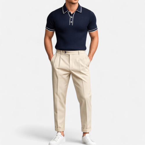 Man wearing a navy polo shirt and beige pants on a white background