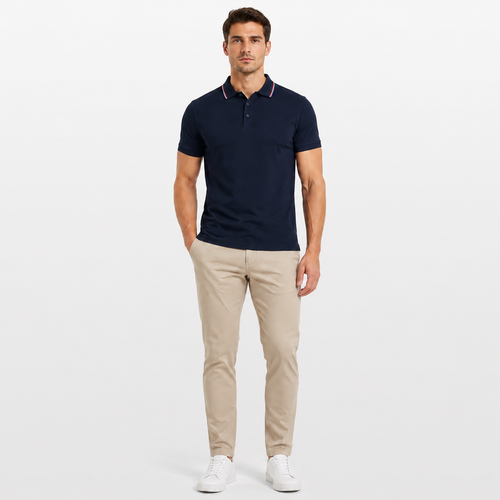 Man wearing a navy polo shirt and beige pants on a white background