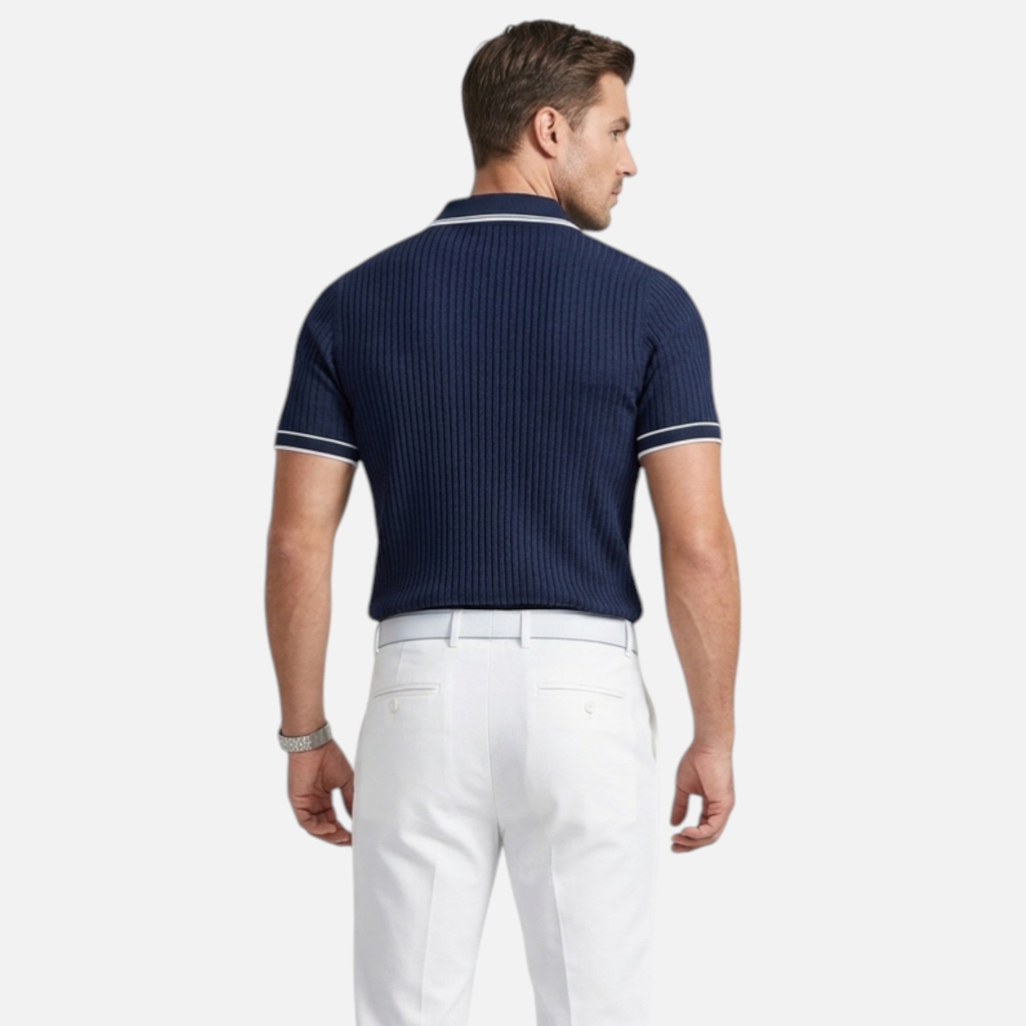 Man wearing a navy polo shirt and white pants on a white background