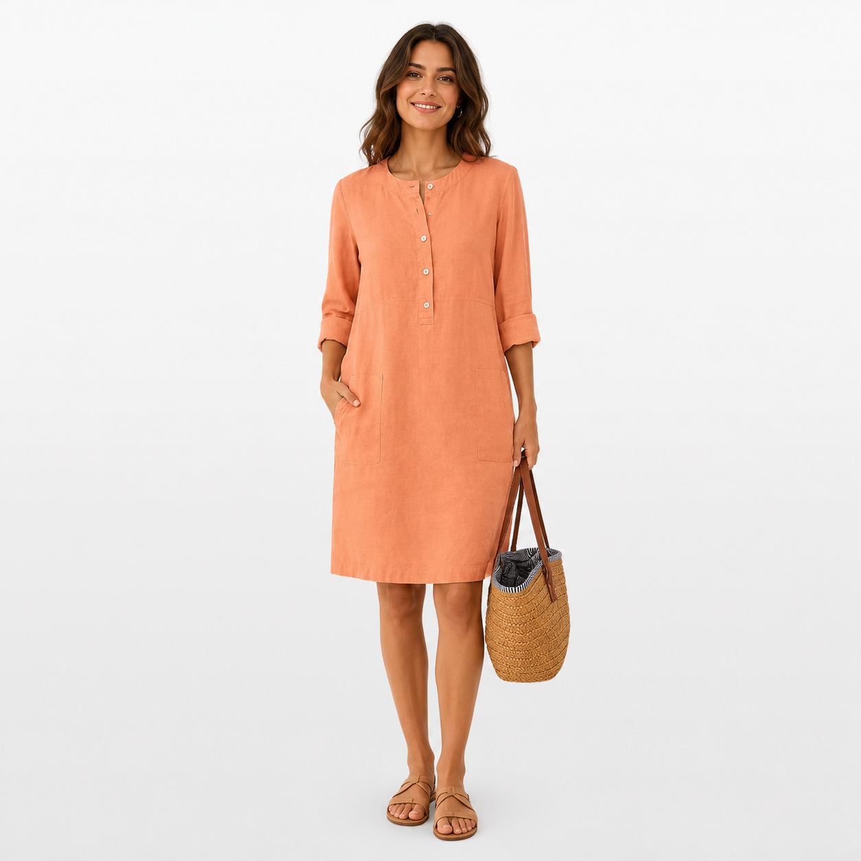 Woman wearing an orange dress holding a woven bag on a white background