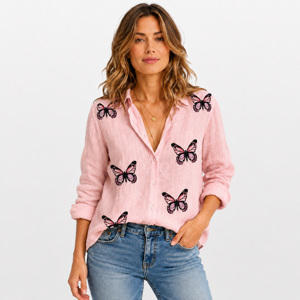 Woman wearing a pink blouse with butterfly designs on a plain background