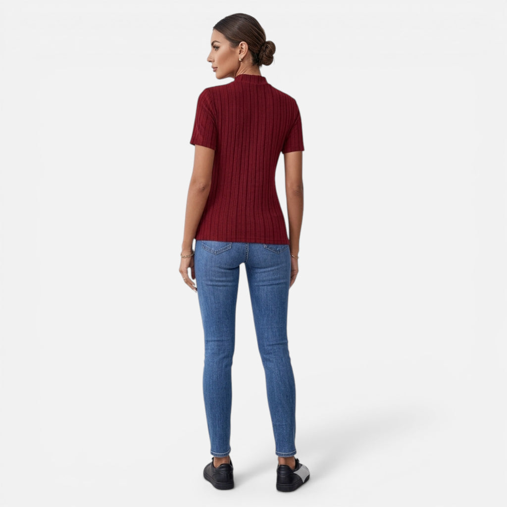 Woman wearing a red ribbed sweater and blue jeans on a white background