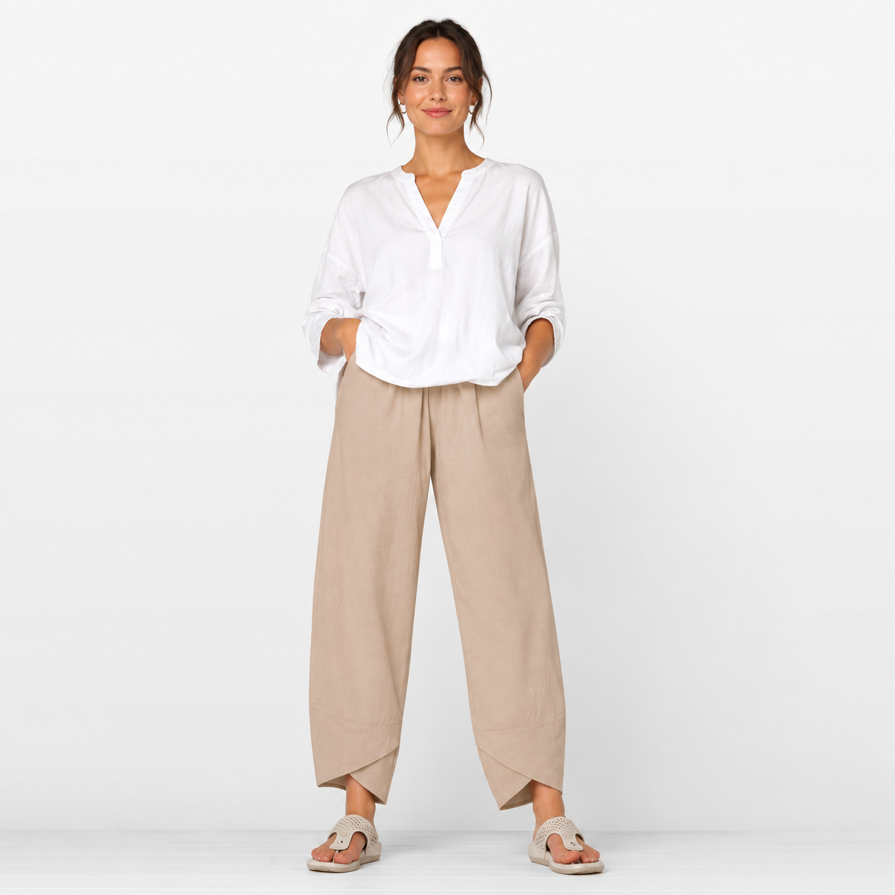 Woman wearing a white blouse and beige pants on a white background
