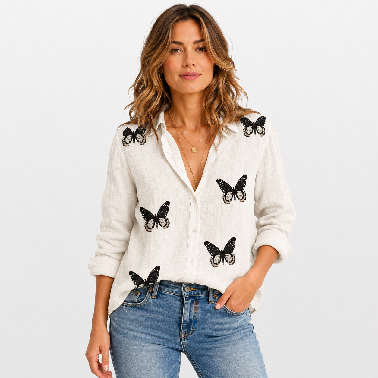 Woman wearing a white blouse with black butterfly patterns and blue jeans on a white background