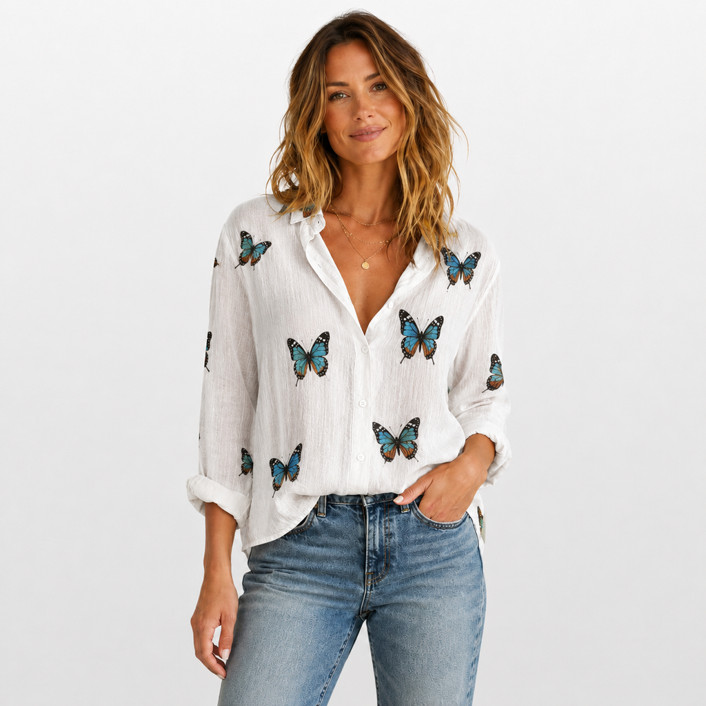Woman wearing a white blouse with butterfly patterns and blue jeans on a light gray background