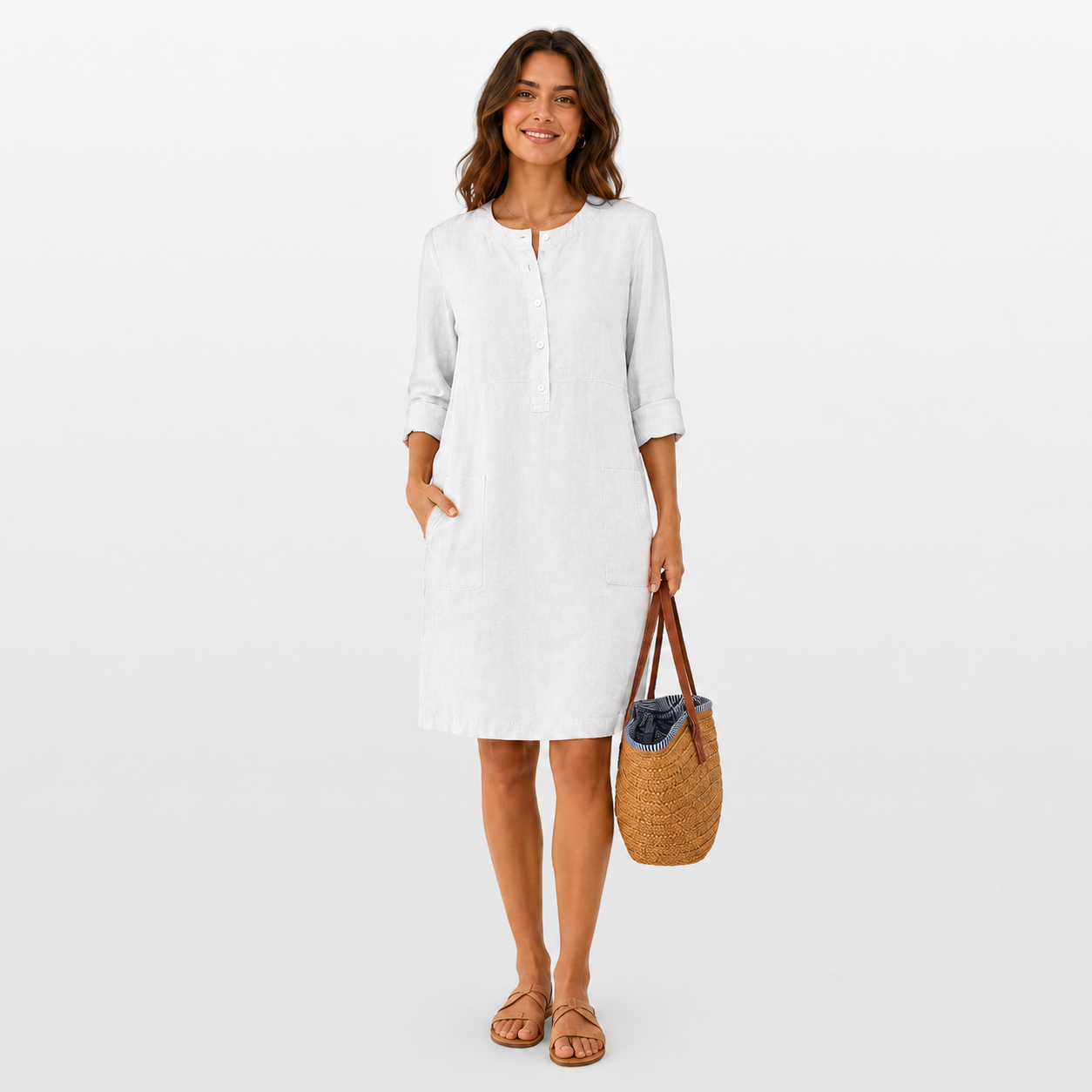 Woman wearing a white dress holding a woven bag on a plain background
