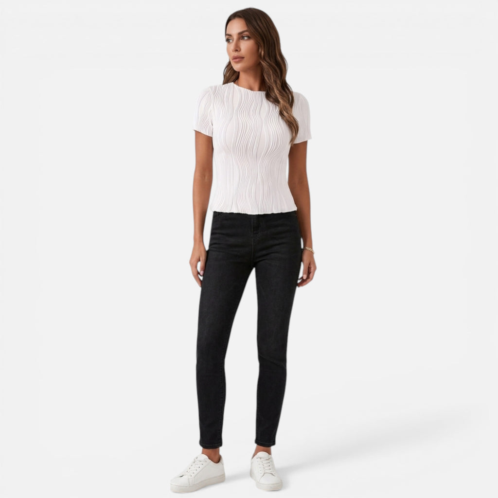 Woman wearing a white ribbed top and black jeans on a white background