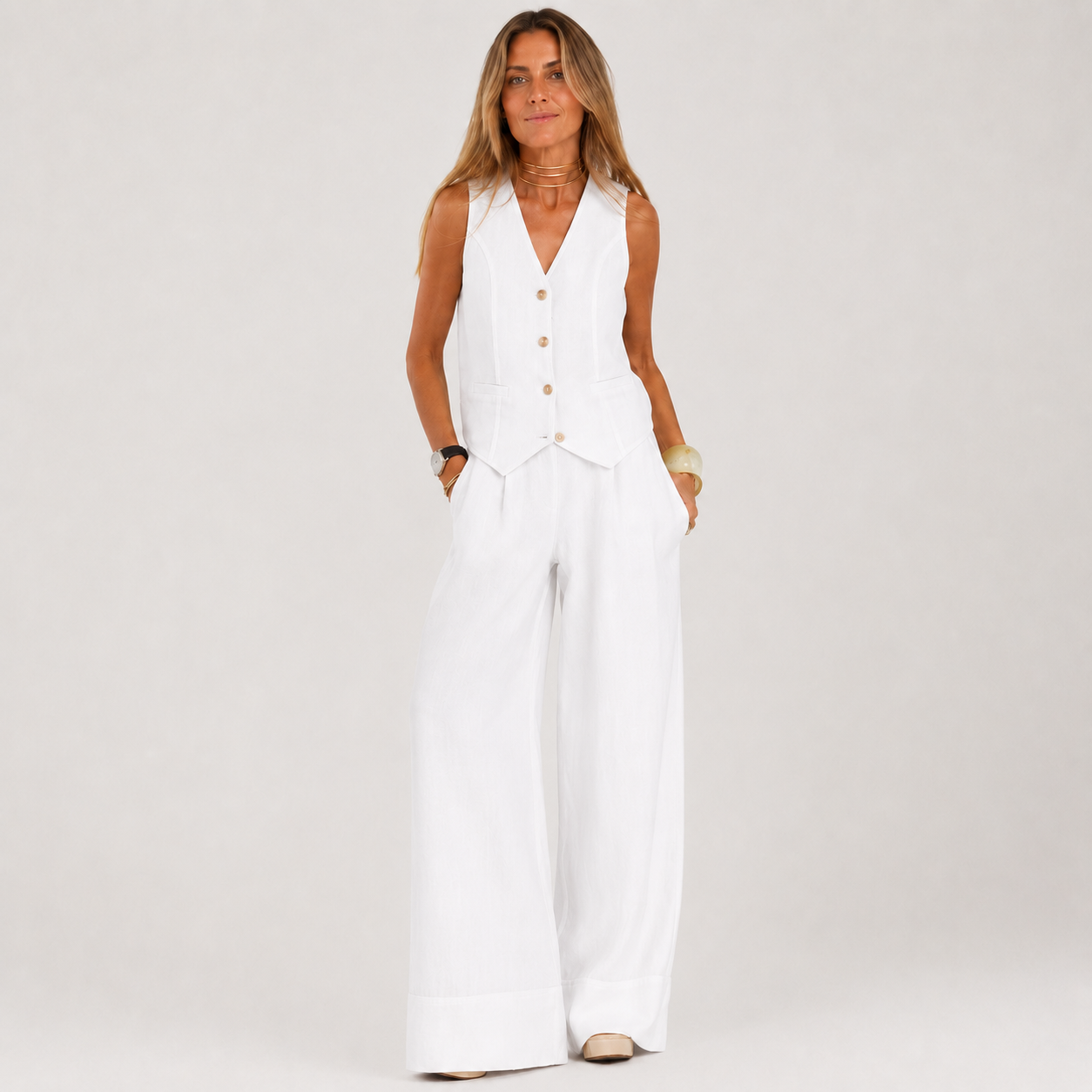 Woman wearing a white sleeveless jumpsuit with buttons on a plain background