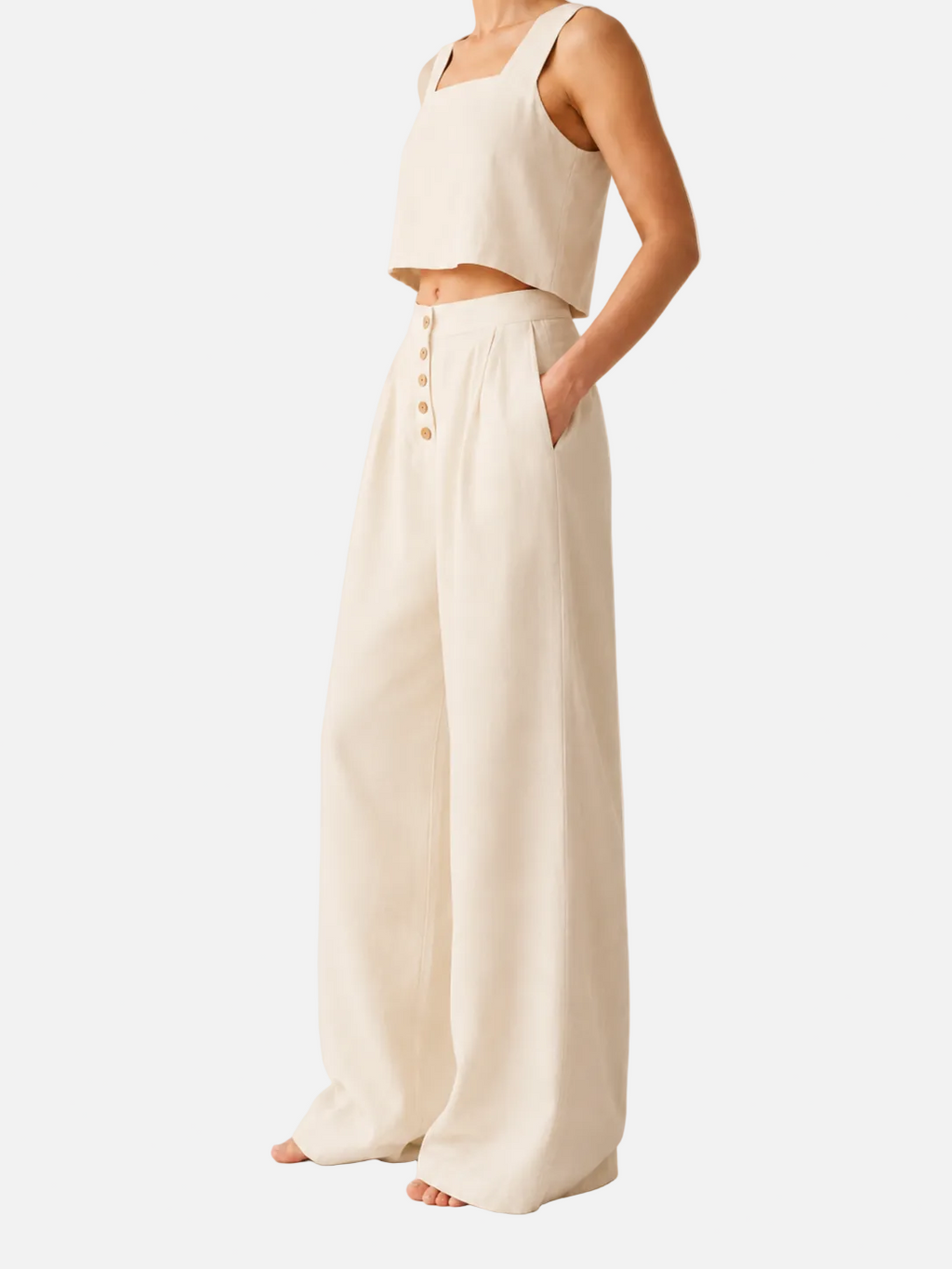 Person wearing a white sleeveless top and wide-leg pants on a plain background